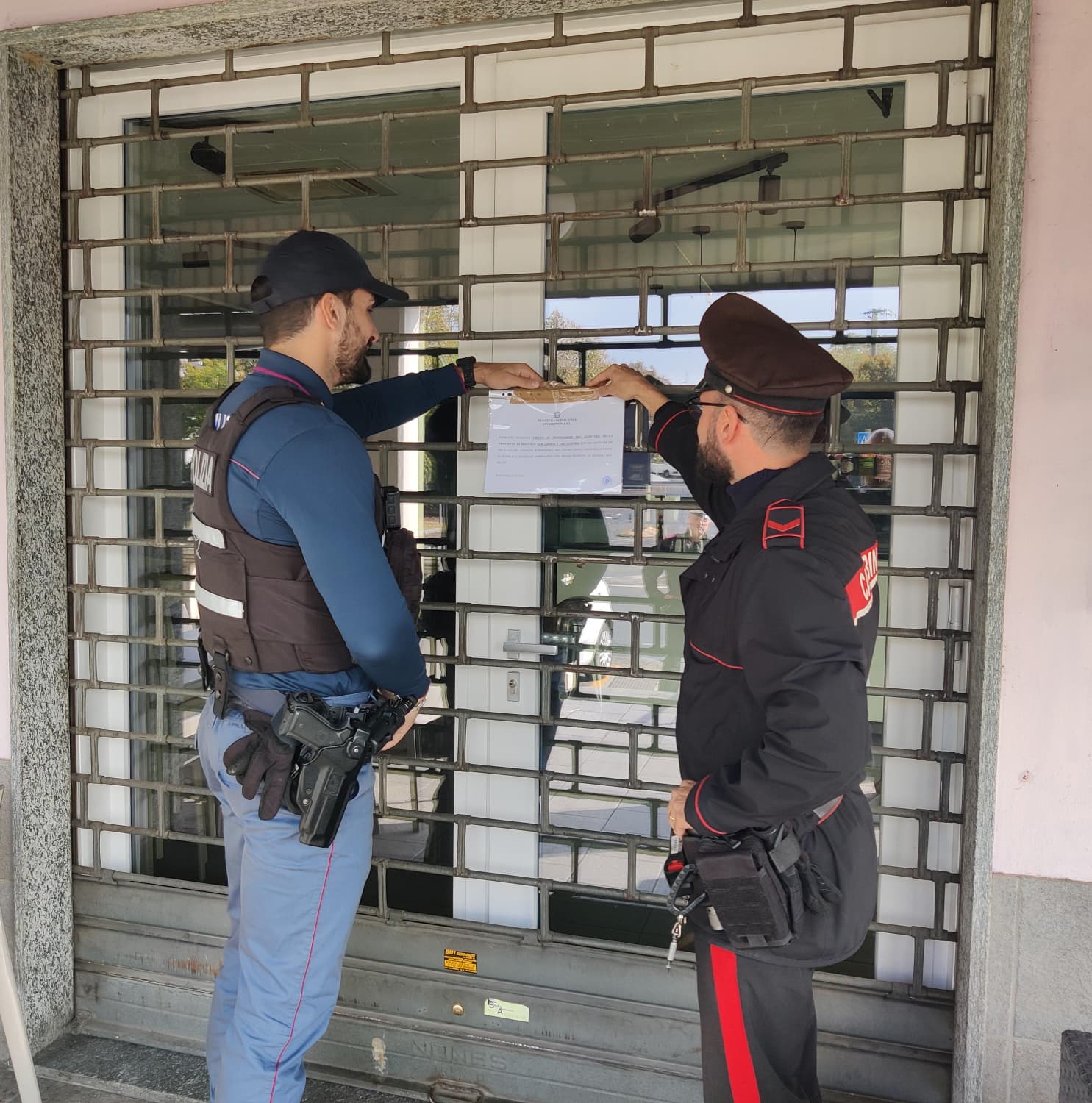 Polizia e Carabinieri affiggono il provvedimento di sospensione della licenza di un bar a Piacenza.